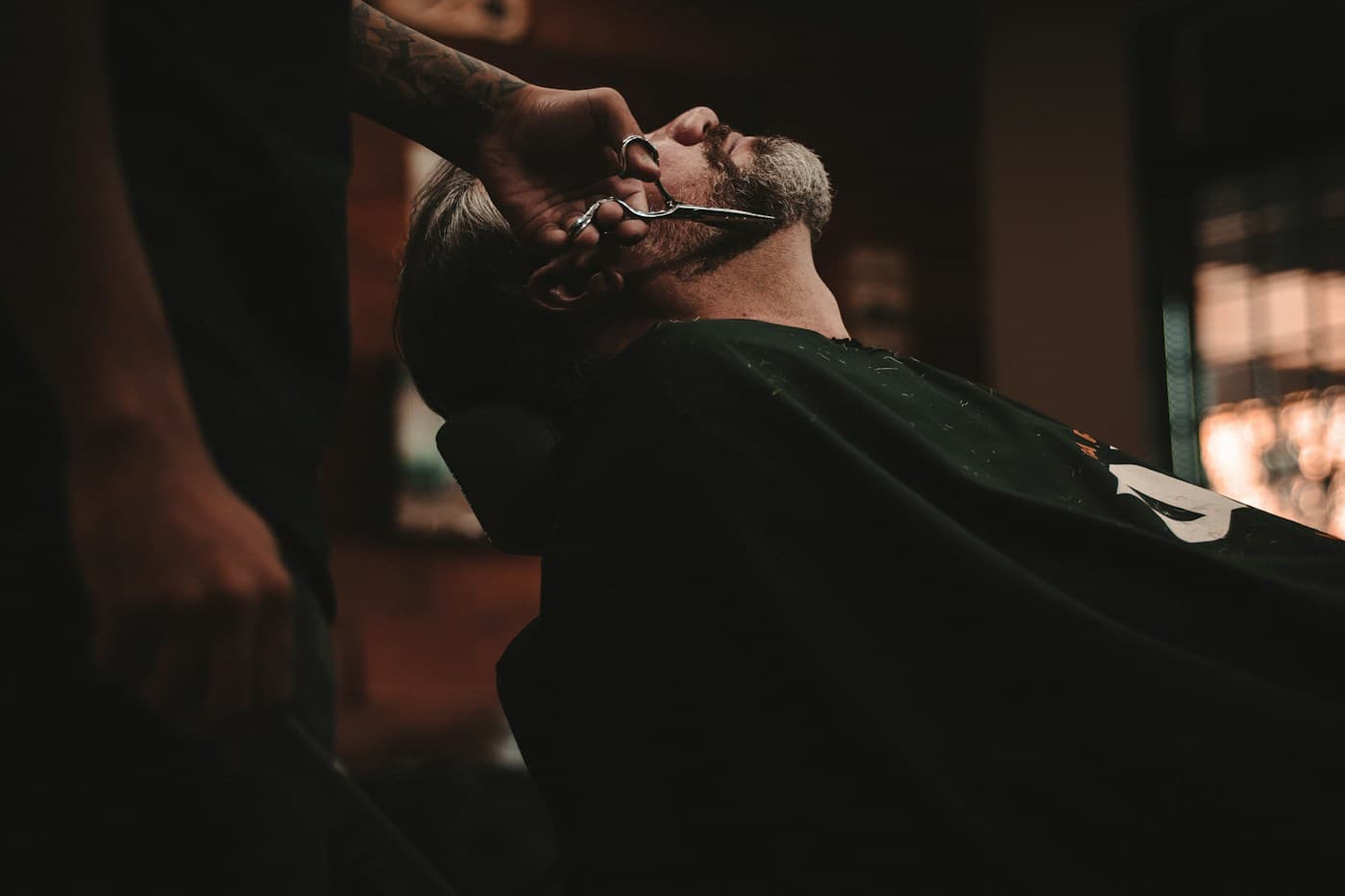 Barber carefully grooming a customer’s beard